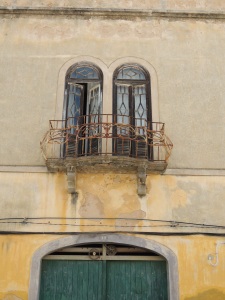 The top half of a green door above which are two arched windows and a balcony
